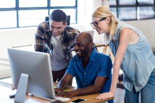 Group of diverse business professionals looking at a Mac monitor 